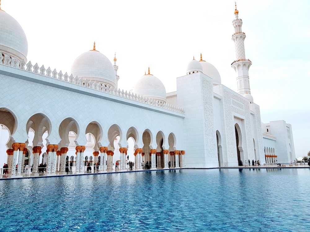 Die schneeweiße Moschee ist von blauem Wasser umgeben